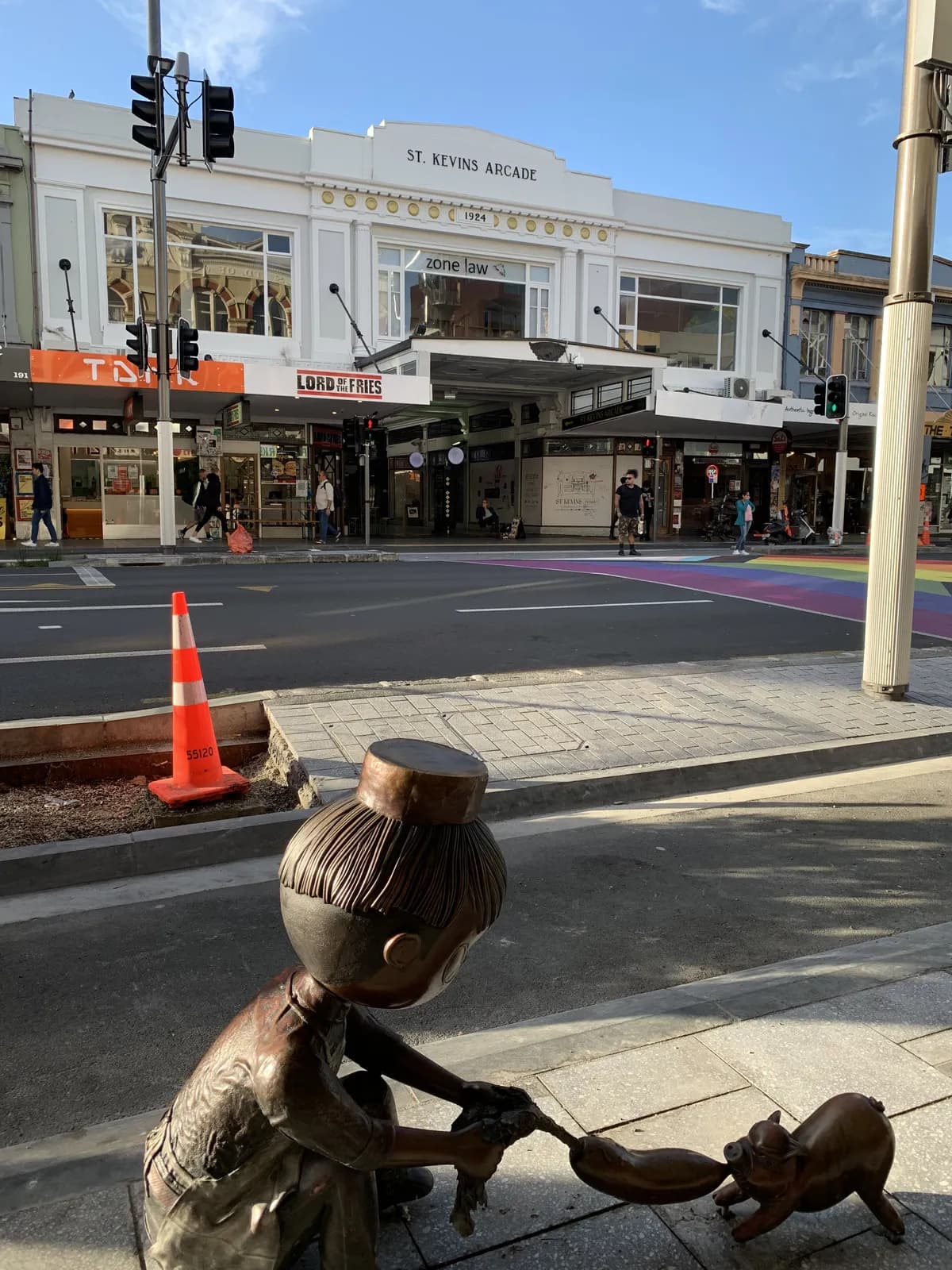 The bronze girl and her dog outside St Kevin's Arcade, 1924. A rainbow crosswalk visible at the intersection behind